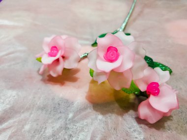 Artificial plastic flower on the shiny pink background
