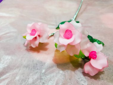 Artificial plastic flower on the shiny pink background