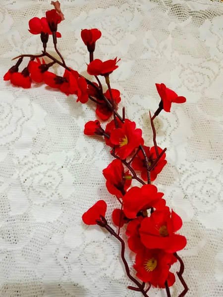 Artificial flowers on the white lace background.