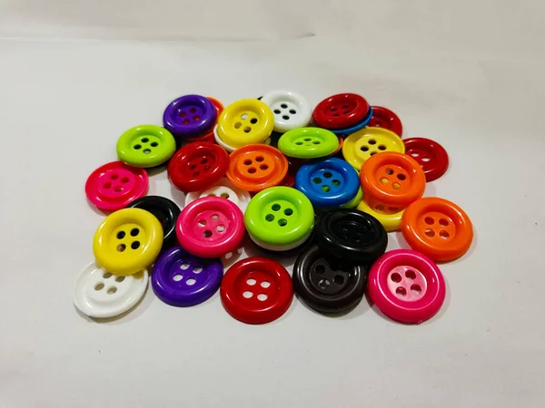 plastic colored buttons on the white background. red, orange, purple blue, black, and green