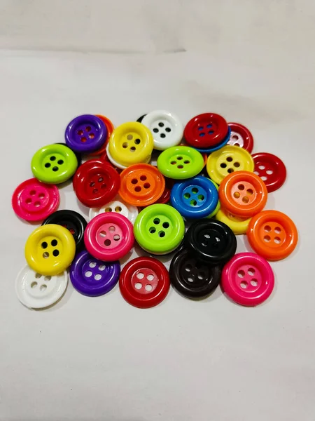 plastic colored buttons on the white background. red, orange, purple blue, black, and green