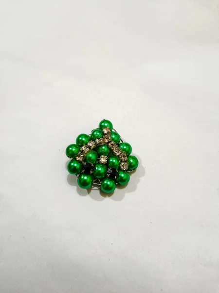 Green beads brooch on the white background