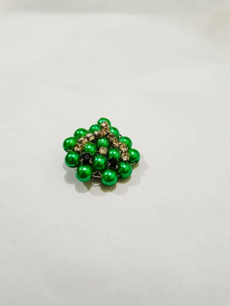 Green beads brooch on the white background