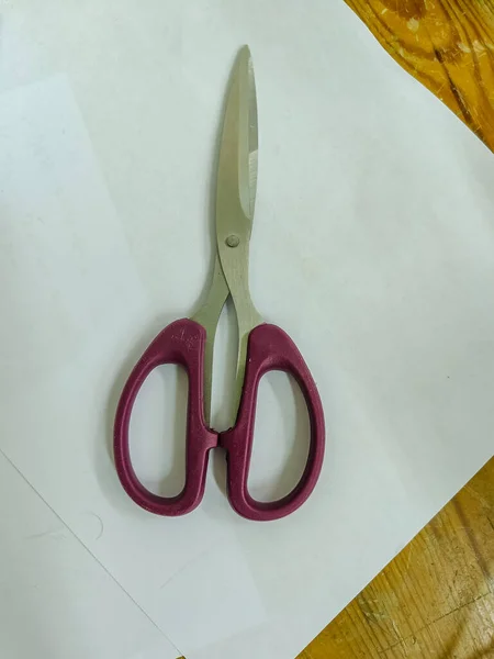 Scissors with purple handle on the white background.