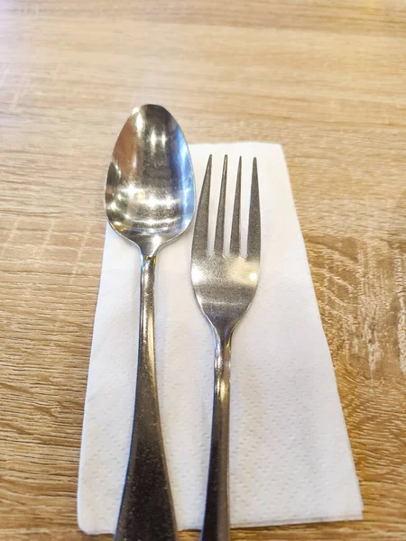 Silverware spoon and fork set with white tissue paper on the table.
