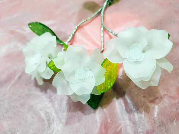 Artificial plastic flower on the shiny pink background