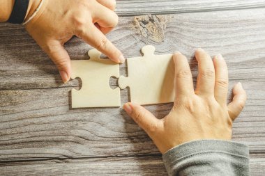 Birbirine bağlanan beyaz yapboz. Takım işi başarı ortaklığı ya da takım çalışması konsepti. Bir grup iş adamı yapboz yapıyor. İş kadını elleri yapbozu birbirine bağlıyor. İş çözümleri, başarı ve strateji kavramı. Kapat