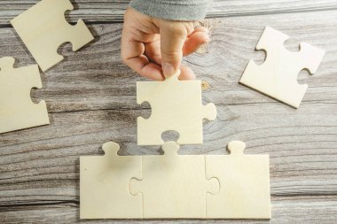 Birbirine bağlanan beyaz yapboz. Takım işi başarı ortaklığı ya da takım çalışması konsepti. Bir grup iş adamı yapboz yapıyor. İş kadını elleri yapbozu birbirine bağlıyor. İş çözümleri, başarı ve strateji kavramı. Kapat