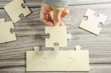 Birbirine bağlanan beyaz yapboz. Takım işi başarı ortaklığı ya da takım çalışması konsepti. Bir grup iş adamı yapboz yapıyor. İş kadını elleri yapbozu birbirine bağlıyor. İş çözümleri, başarı ve strateji kavramı. Kapat