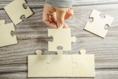 Birbirine bağlanan beyaz yapboz. Takım işi başarı ortaklığı ya da takım çalışması konsepti. Bir grup iş adamı yapboz yapıyor. İş kadını elleri yapbozu birbirine bağlıyor. İş çözümleri, başarı ve strateji kavramı. Kapat