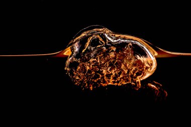 Yağ sıçraması ve hava kabarcıkları siyah arka planda izole edilmiş. Sarı Altın rengi su dalgası soyut arkaplan izole