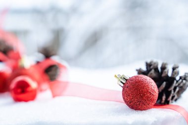 Kışın Noel 'i, kar kurdeleli Noel baloları, kış tatili konsepti. Noel kırmızı topları, altın toplar, çam ve kar taneleri kar altında süslemeler