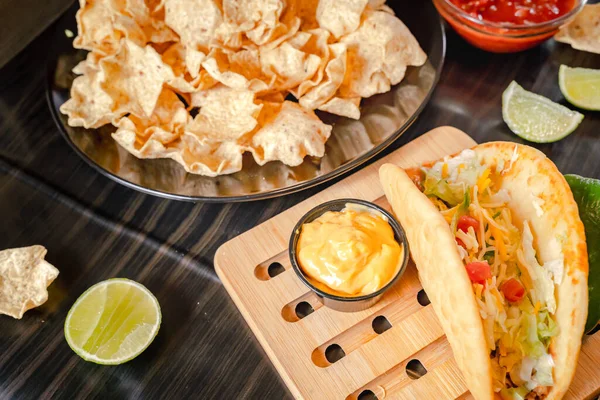 stock image Close up Hand hold chip dip tomato salsa with plate with taco, nachos chips and tomato dip. Spicy Nachos  on rustic wooden background