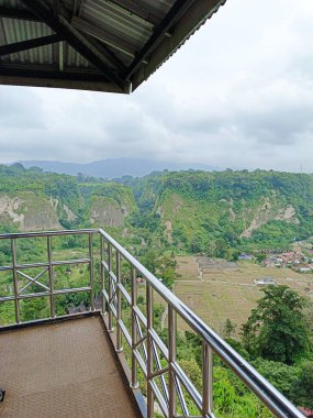 a view of a valley from a balcony with a view of the mountains and a town below in Bukittinggi West Sumatra clipart