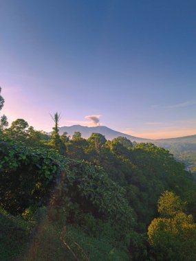 Lanscape view nature with mountain, view of Mount Marapi erupting in the morning clipart