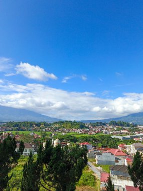 Dağlar arasındaki bulutların portresi bir tepenin tepesinden alınmış ve şehrin manzarasını gösteriyor.
