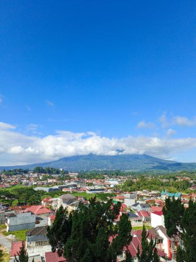 Portrait view of clouds between mountains taken from the top of a hill and showing views of the city clipart