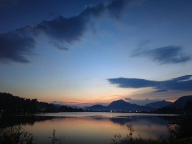 Akşam günbatımının yansıması güzel bir gölün arka planında mavi turuncu gökyüzü