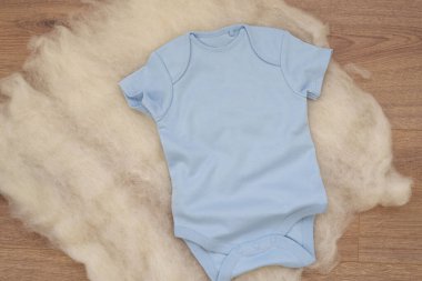 Ahşap arka planda mavi bebek tulumu modeli. Boş bebek kıyafetleri maket gibi. Düz yatmış stok fotoğrafı.