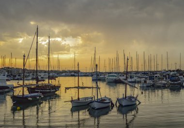 Akdeniz limanında gün batımı, oşlar ve gri bulutlu gökyüzü.