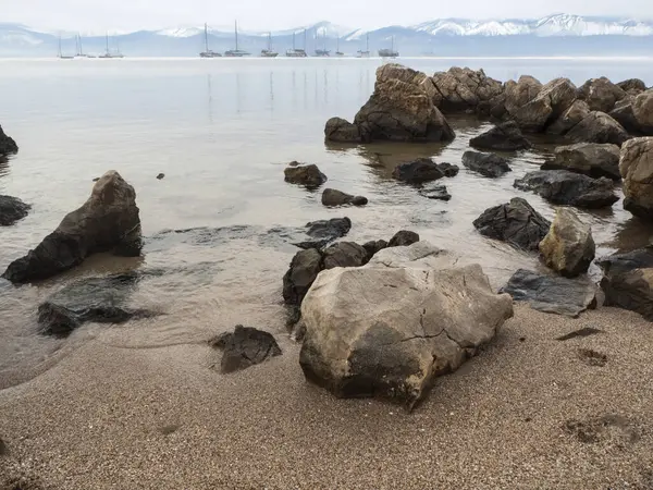 Ön planda kayalar, arka planda dağlar olan manzara.
