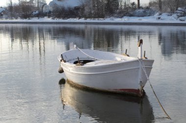 Sakin suları ve karlı dibi olan bir gölde tekne.