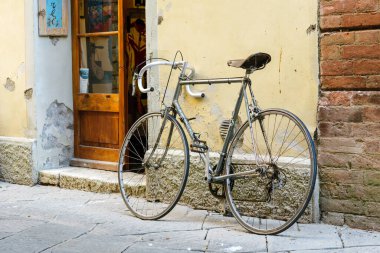Buonconvento, Siena, İtalya - 24 Ağustos 2024: Tarih Merkezi 'nin ana caddesinde duvara yaslanmış klasik yarış bisikleti