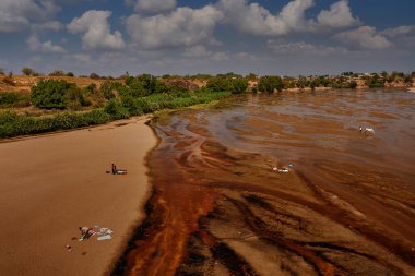 Madagaskar 'daki nehir manzarası. Büyük nehirde çamaşır yıkamak, mavi gökyüzü ve bulutla güneşli bir gün. Madagaskar 'daki insanlar, sudaki kadınlar..