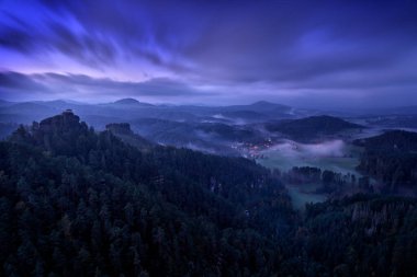Çek manzarası. İsviçre 'nin Bohemian parkındaki sonbahar vadisinde soğuk sisli bir sabah güneşi. Tepede koyu sisli odunlu tepe, Mariina vyhlidka, Ceske Svycarsko, Çek Cumhuriyeti.