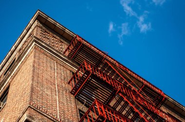 New York 'ta yangın çıkışı ve mavi gökyüzü olan eski kırmızı tuğla bina.