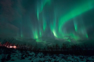 Norveç 'teki yeşil dağların üzerinde Aurora Borealis