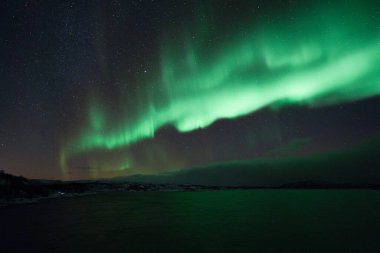 Kuzey ışıkları aurora borealis Norveç 'teki yeşil dağların üzerinde