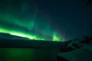 Kuzey ışıkları aurora borealis Norveç 'teki yeşil dağların üzerinde