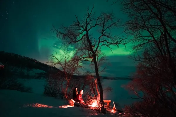 Bir adam dağlarda kamp ateşinde oturuyor..