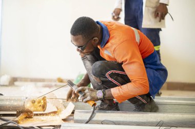 Afrikalı bir adamın çalışan bir çevrede kaynak malzemesi tutarken görüntüsü ışıl ışıl. Metal üretim kavramı.