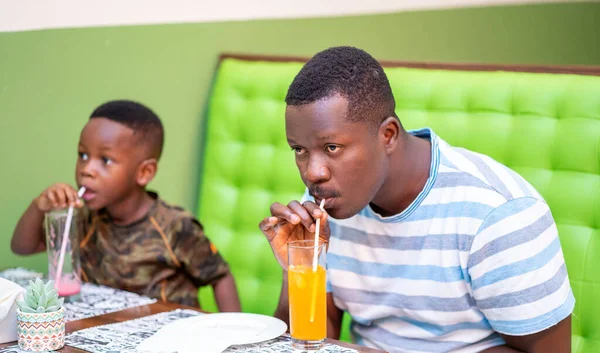Porträtt Ung Afrikansk Man Och Söt Liten Pojke Dricka Drycker — Stockfoto