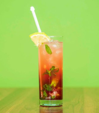 glass of tasty lemonade with lemon slices on table on blurred background