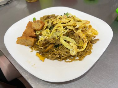 Geleneksel Endonezya usulü kızarmış erişte, kızarmış yumurta dilimi ve tavuklu et.