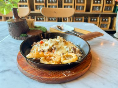 Pirinç, sebze ve etle dolu tava yemeği kremalı sos veya satranç peyniri sosu ve mermer bir yüzeye yerleştirilmiş gevrek soğan halkaları ile kaplı. Lezzetli ve sağlıklı bir yemeğe benziyor.