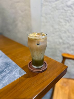 Kremalı bir katmanla kaplı bir bardak ferahlatıcı buzlu kahve, modaya uygun, rahat bir kafede sıcak günler için ideal.