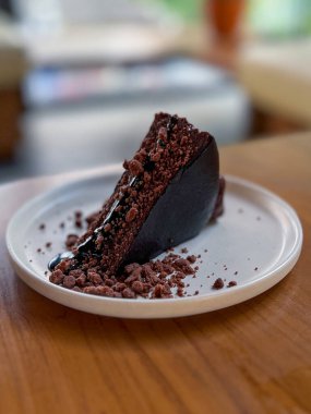 Lezzetli bir dilim çikolatalı pasta güzel bir şekilde beyaz bir tabakta sunuldu dikkatlice sade ahşap bir masaya yerleştirildi.