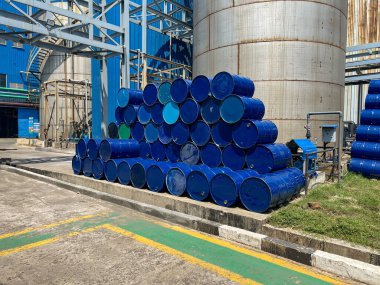 Endüstriyel bir tesis içinde dikkatlice organize edilmiş mavi fıçı kümesi düzgün bir şekilde düzenlenmiştir.