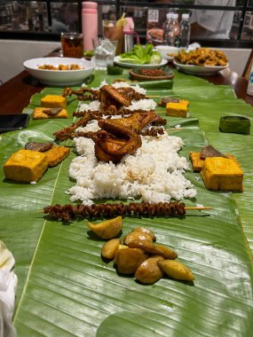 Muz yaprakları üzerinde rengarenk bir dizi yemek, herkes için zengin bir kültür ziyafeti deneyimi sunuyor.