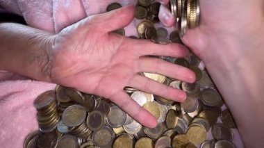 Genç el ağır çekimde eski ellere bozuk para atıyor.