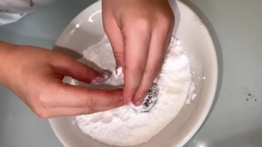 Biscuit being covered by flour in plate with a persons hand