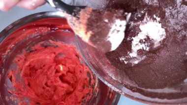 Cocoa powder is placed in the dish with red cream, ready to be mixed