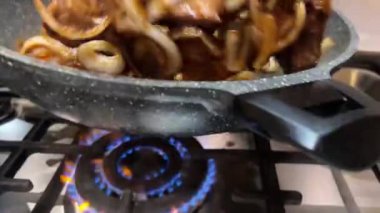 Soğanlı lezzetli et, mutfaktaki tencerede ağır çekimde karıştırılır.