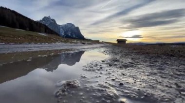 Su birikintisi ve çamurun içindeki dağın yansıması.