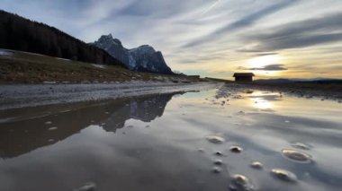 Puddle in the mountains reflects the evening landscape
