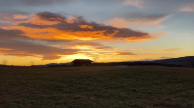 Silhouette of the wooden house at sunset on the meadow